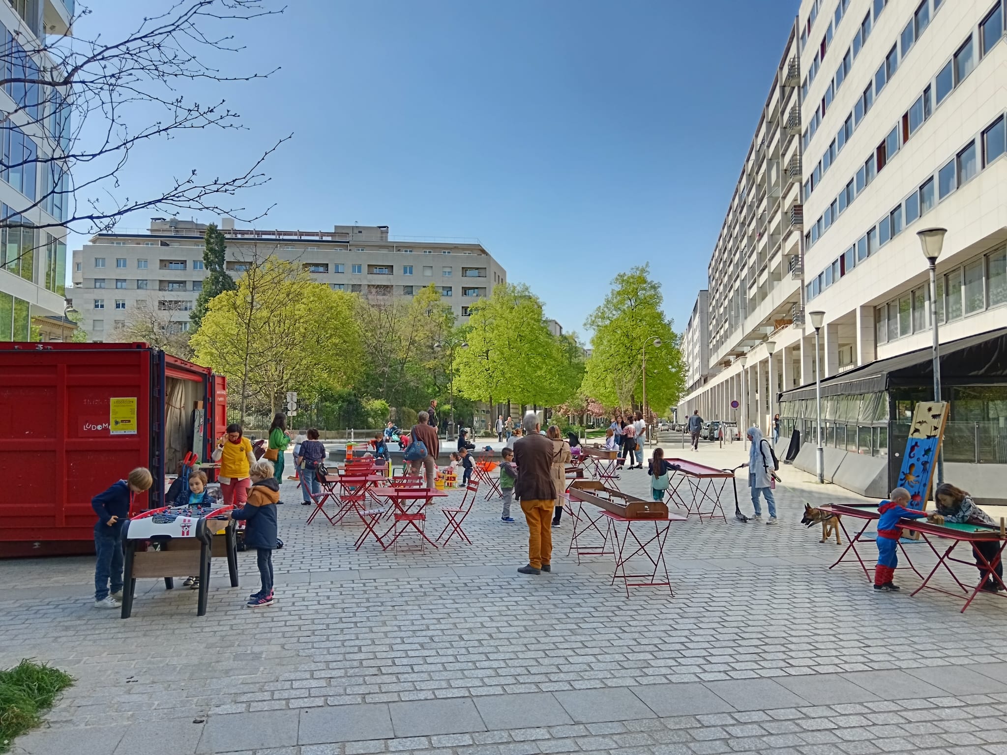 Une place piétonne peuplée d'enfants jouant à une ludomobile