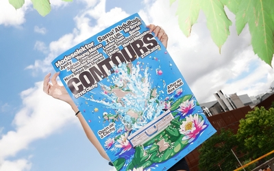Une femme tient l'affiche du Contours Festival 2025