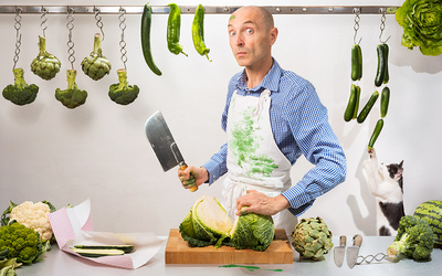 Mise en scène d'un boucher vert, entouré de légumes verts et coupant un choux.