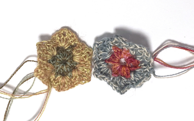 Photographie de deux fleurs colorées, créées avec la technique du crochet oya. 