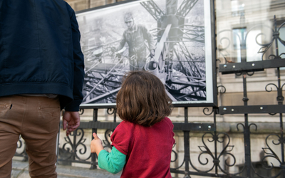Une enfant et un adulte devant l'expo David Turnley sur les grilles de l'Hôtel de Ville. 