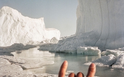 Photo représentant le signe des rockeurs en premier plan, puis un paysage glacier