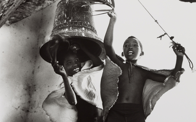 Photo sépia représentant deux enfants noirs jouant avec un clocher