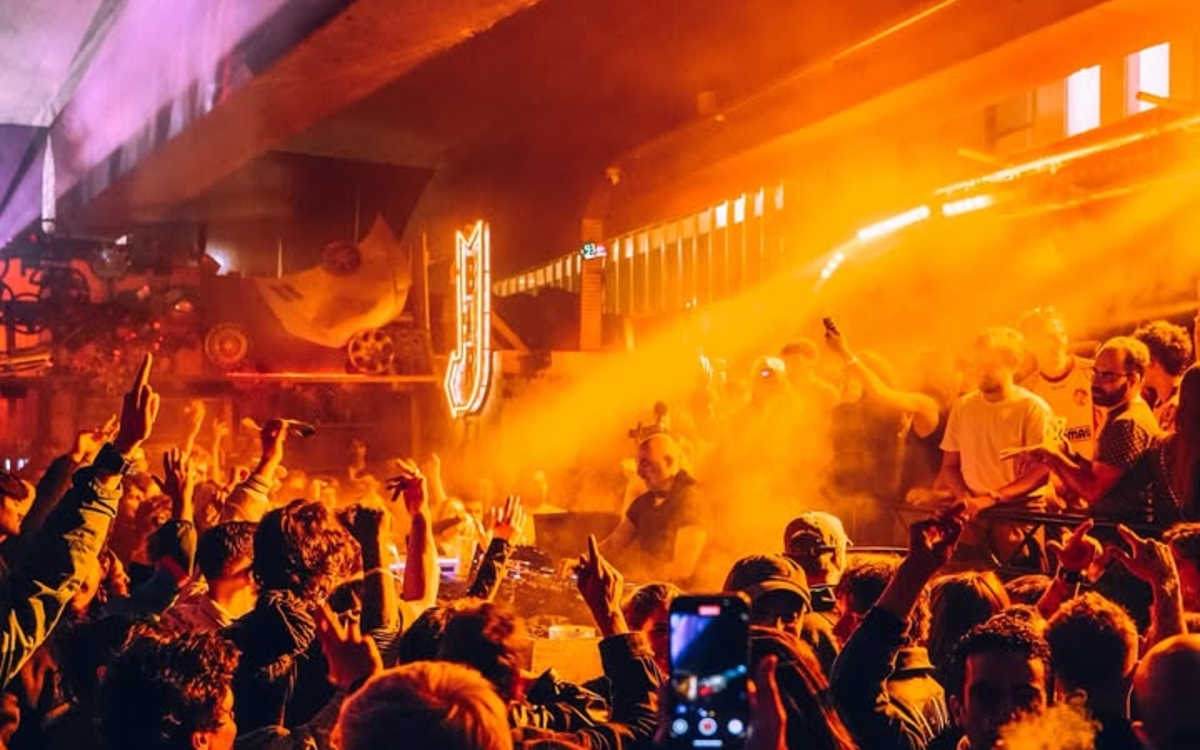 Foule devant un DJ, photo aux tons orangés