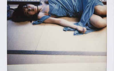 Polaroid représentant une femme asiatique habillée d'une robe bleu vaporeuse allongée sur le sol