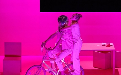 Sur une scène de théâtre, un couple s'amusent sur un vélo