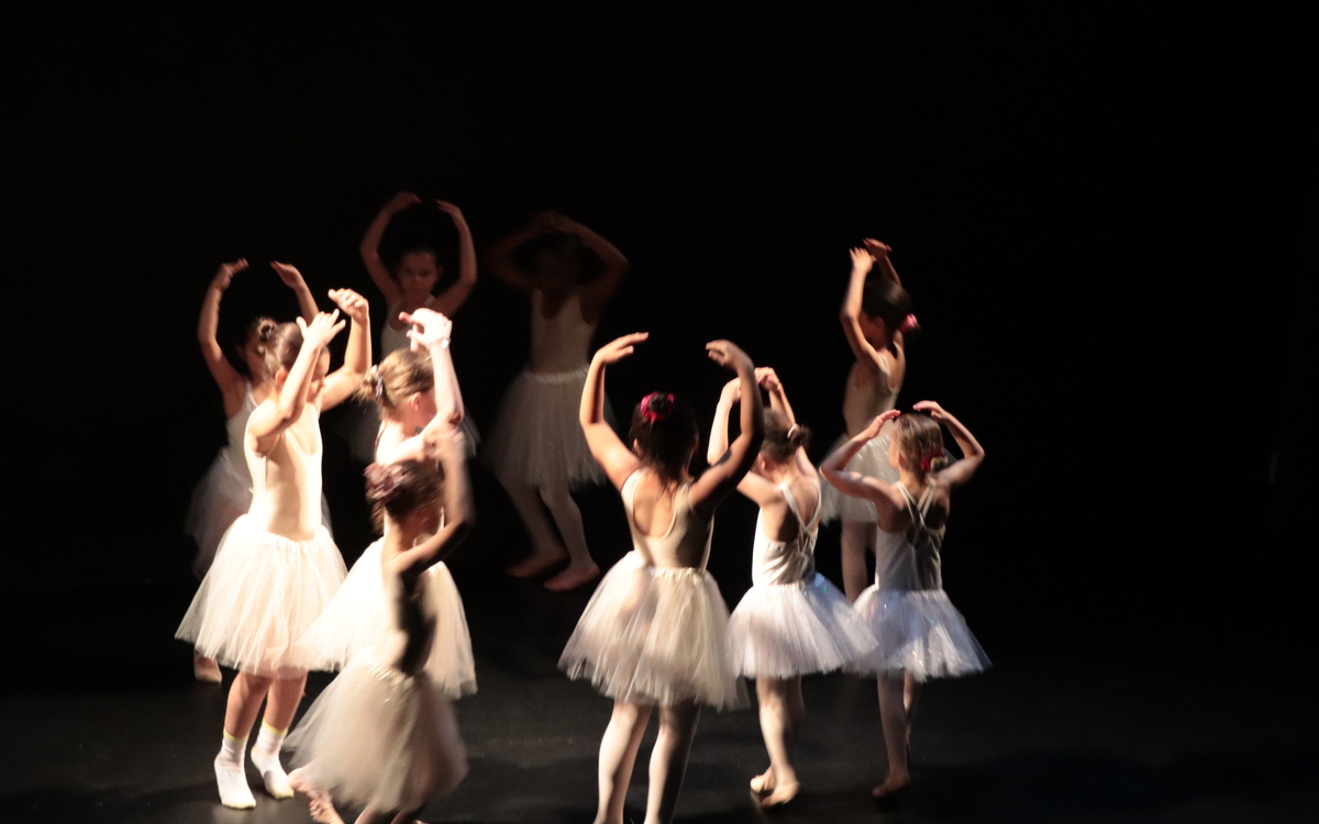 Des petites filles en tutu blanc dansent sur une scène