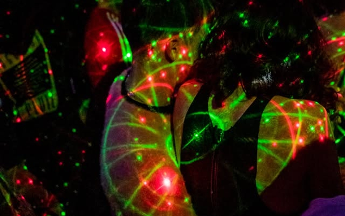 Un couple s'enlace sous des néons dans un club