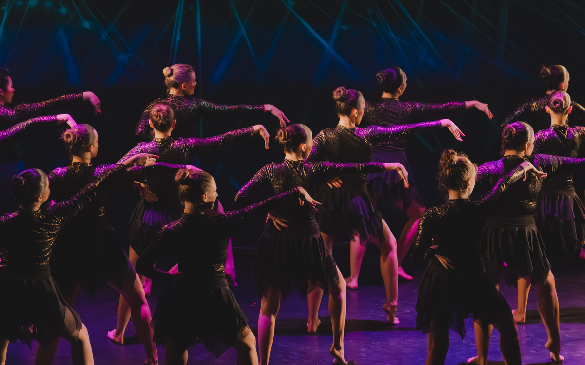 Des danseuses sont de dos et lèvent la main droite dans des couleurs sombres et violettes