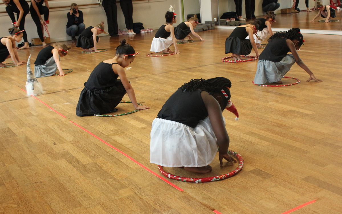 Des petites filles dansent accroupies au sol lors d'un spectacle