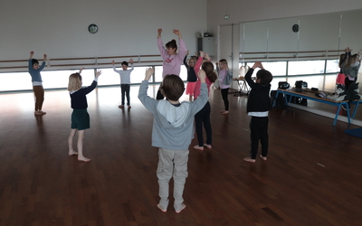 Des enfants entourent leur professeure et dansent en levant les bras