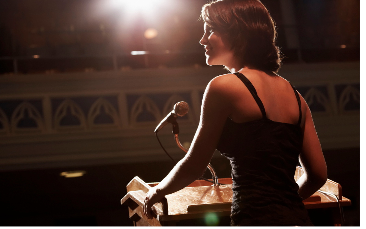 Une femme parle au micro devant un pupitre