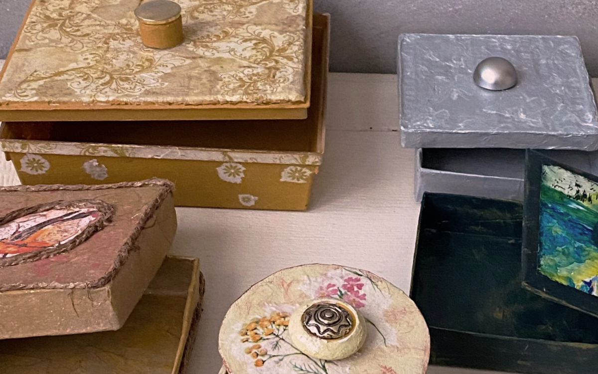 Photographie de quatre boîtes qui ont été customisées et upcyclées avec des papiers de couleur, de la peinture etc. Créations qui ont été réalisées lors de l'atelier décoration de boîtes.