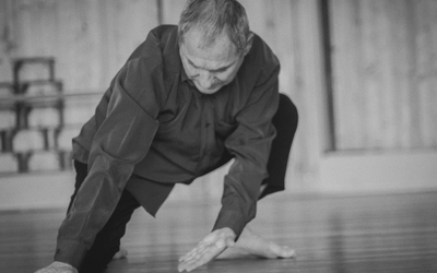 Un homme danse dans un studio de danse, il est pied nu et proche du sol.