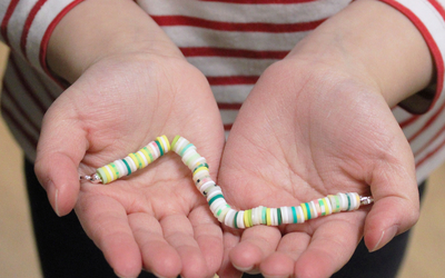 Photographie des mains d’une petite fille tenant un bracelet lors de l’atelier spécial enfant : bijoux.