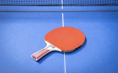 Photo d'une raquette de ping-pong rouge sur une table bleue.