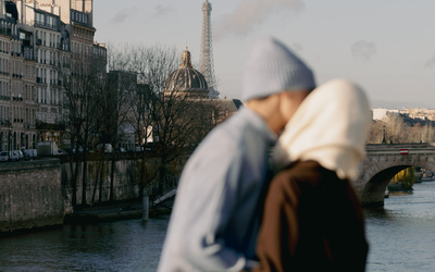 Un couple sur un pont ensoleillé de Paris.