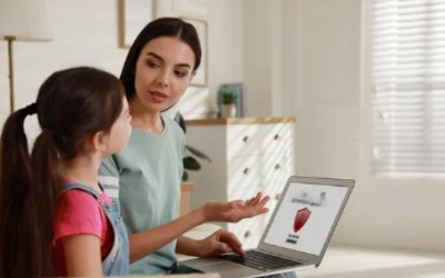 une femme explique à une petite fille en montrant un ordinateur