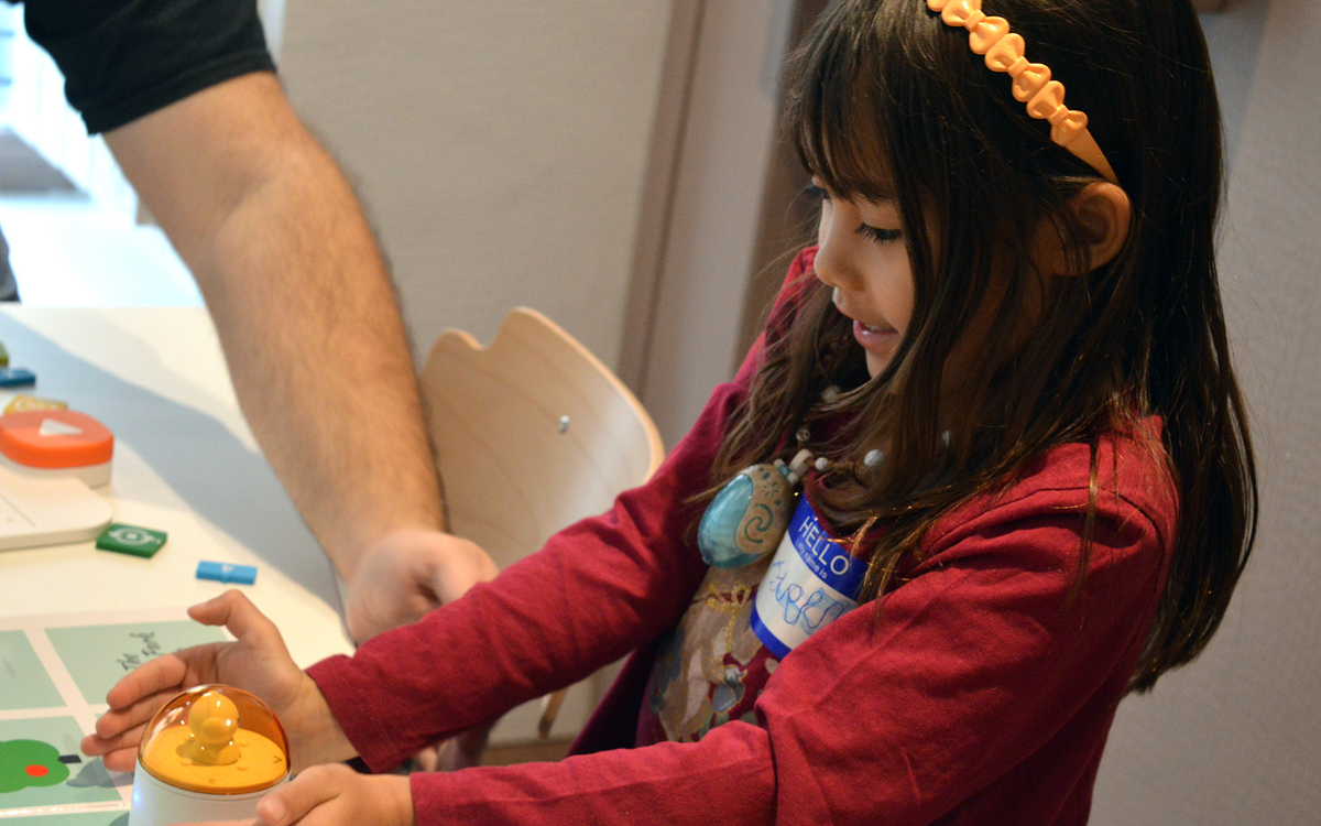 Une fille tient un robot jaune et sourit