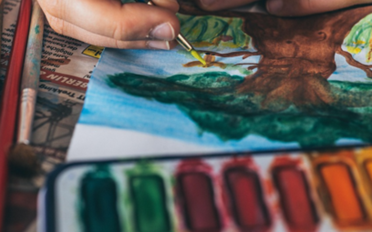 Une palette d'aquarelle et une personne qui peint un arbre
