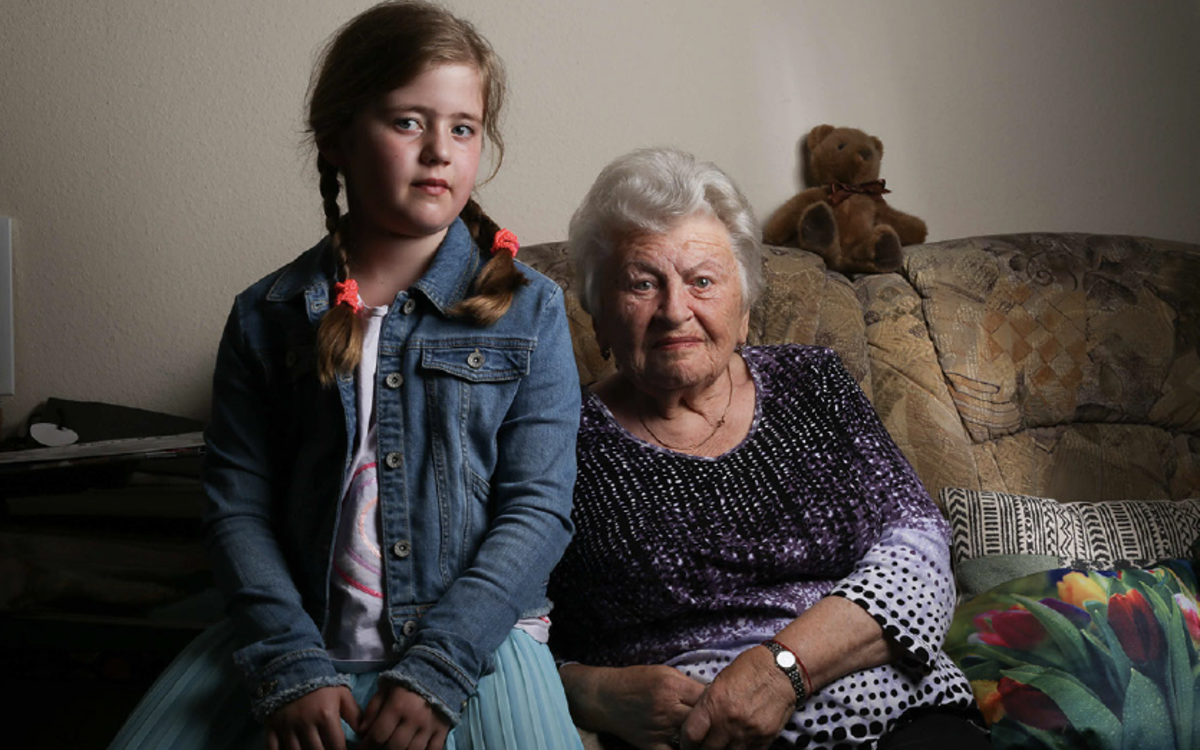 Une jeune fille de 13 ans pose avec une dame âgée sur un canapé