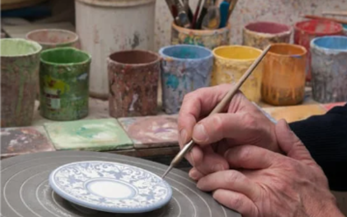 Des mains peignent une pièce en porcelaine
