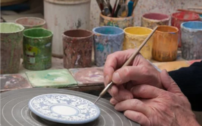 Des mains peignent une pièce en porcelaine