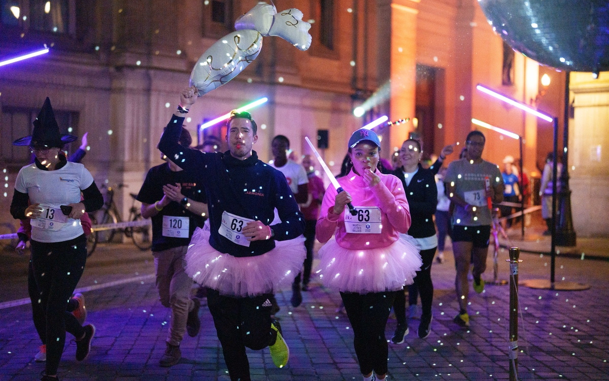 Coureuses et coureurs sur la piste éclairée par des lumières colorées lors de la Nuit des Relais Paris en 2024