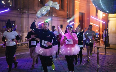 Coureuses et coureurs sur la piste éclairée par des lumières colorées lors de la Nuit des Relais Paris en 2024