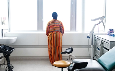 Femme regardant par la fenêtre depuis sa chambre d'hôpital