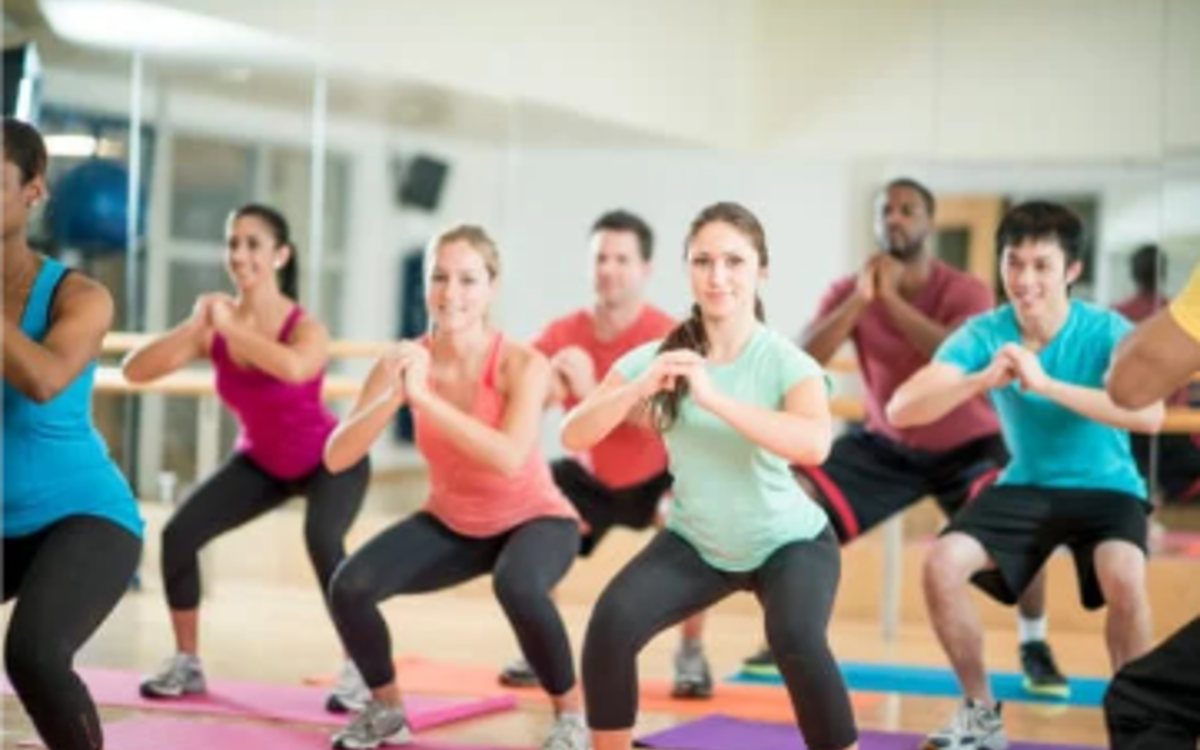 Des personnes font des squats dans un cours de fitness