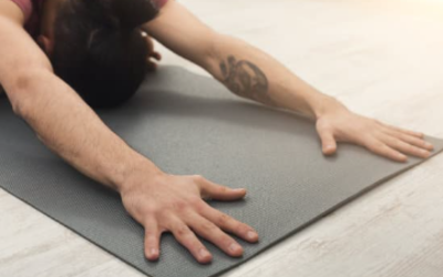 Une personne s'étire en stretching sur un tapis