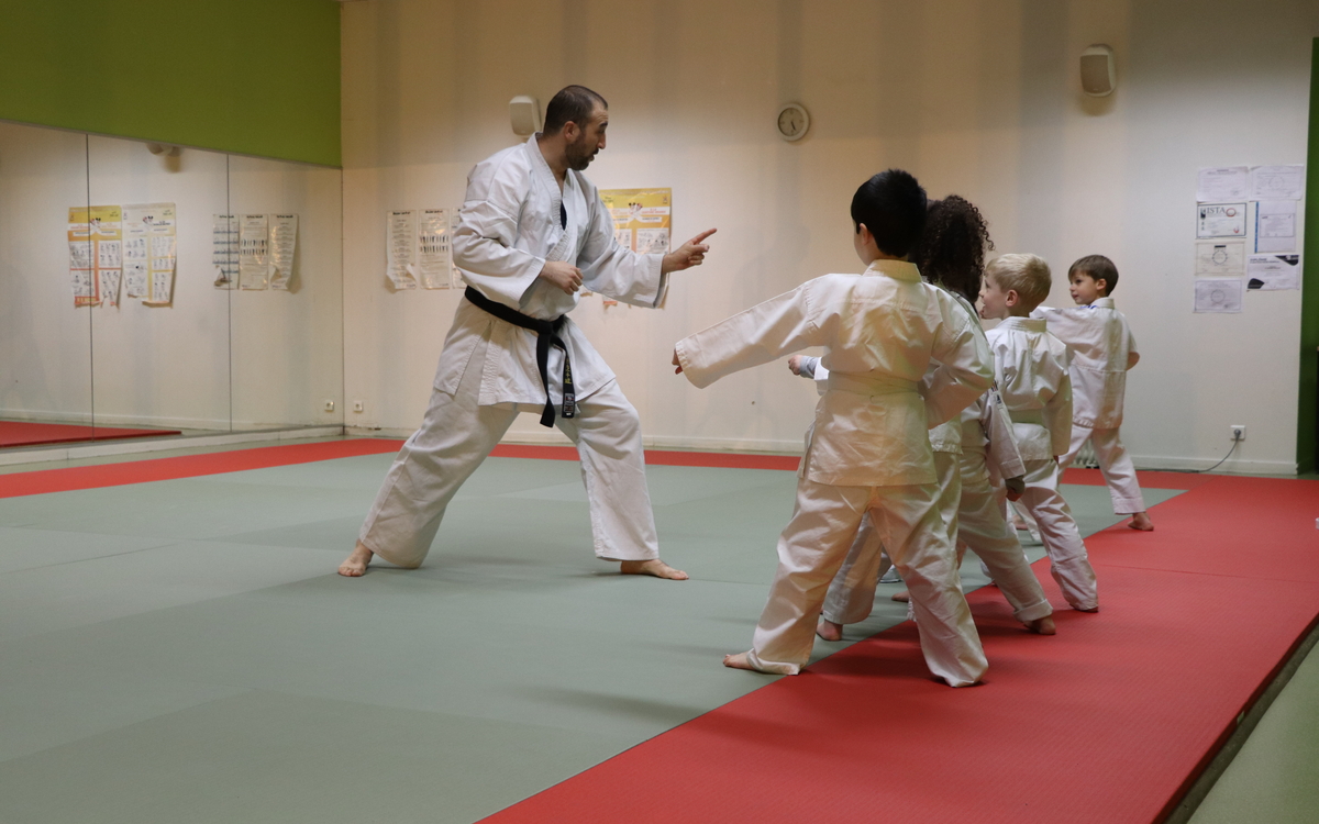 Un professeur en kimono expliquent aux enfants en kimono les arts martiaux