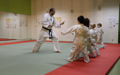 Un professeur en kimono expliquent aux enfants en kimono les arts martiaux