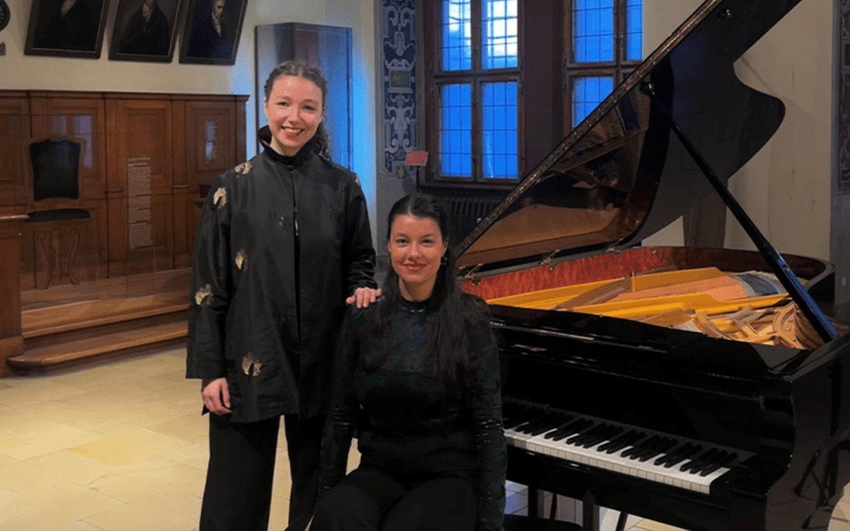 Les musiciennes Rachel Ridout (soprano) et Ceren Senyücel (piano) dans une salle da concert à côté d'un grand piano