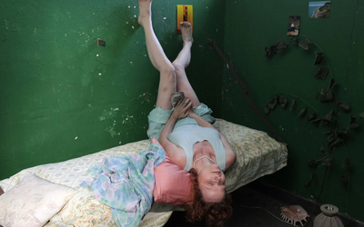 Photographie de Pauline Curnier Jardin qui représente une femme allongée dans une chambre tenant une chaussure entre ses jambes