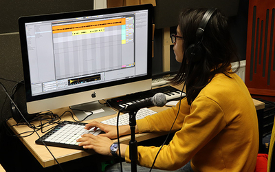 Une adolescent est dans un studio son sur ordinateur 