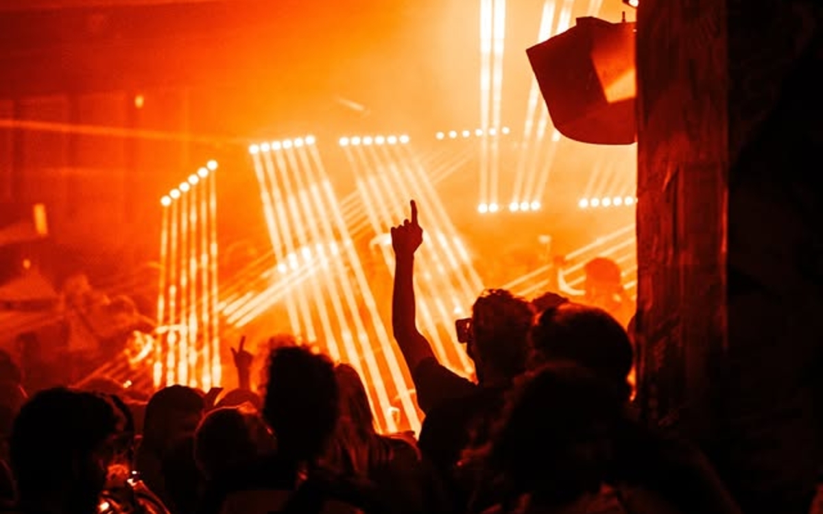 Photographie d'une foule dansant dans un club avec des lumières orange