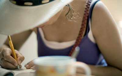Une personne écrivant une carte postale à une terrasse de café. 