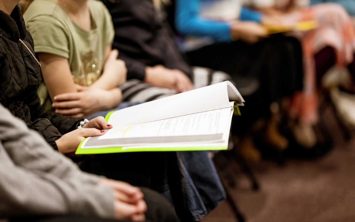 Un groupe de personnes dont on ne voit pas les visages est réuni autour d'un livre