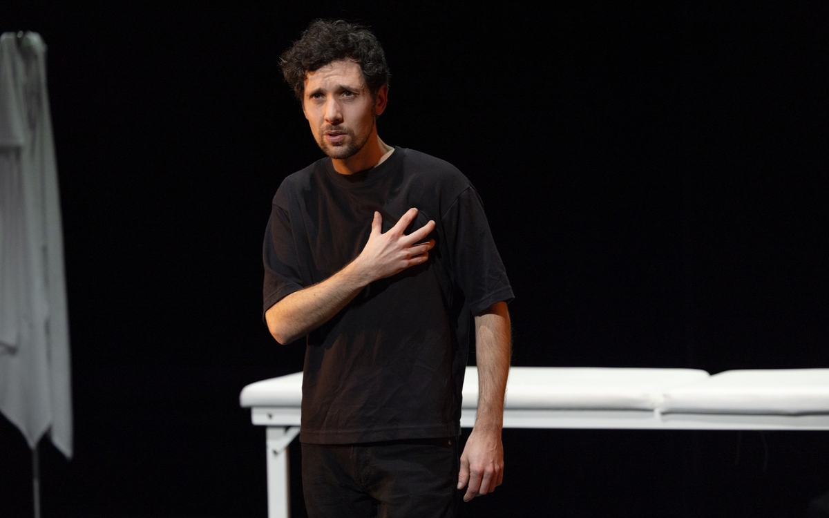 Un jeune homme se tient la poitrine. Derrière lui, tout un décor fait passer à un hôpital.