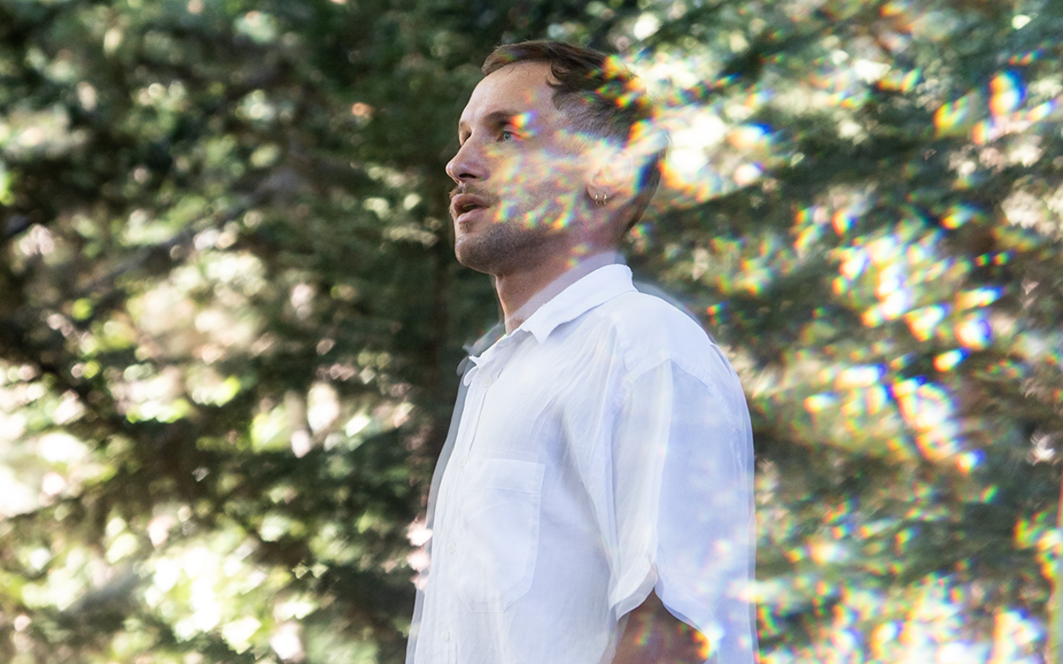 Nicolas Barry est au milieu d'un paysage verdoyant, lumineux et flou.
