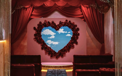 De banquettes confortables, un tapis zebré, des rideaux rouges, et au centre de la scène, une couronne de roses rouges en forme de coeur dans laquelle se trouve un ciel bleu