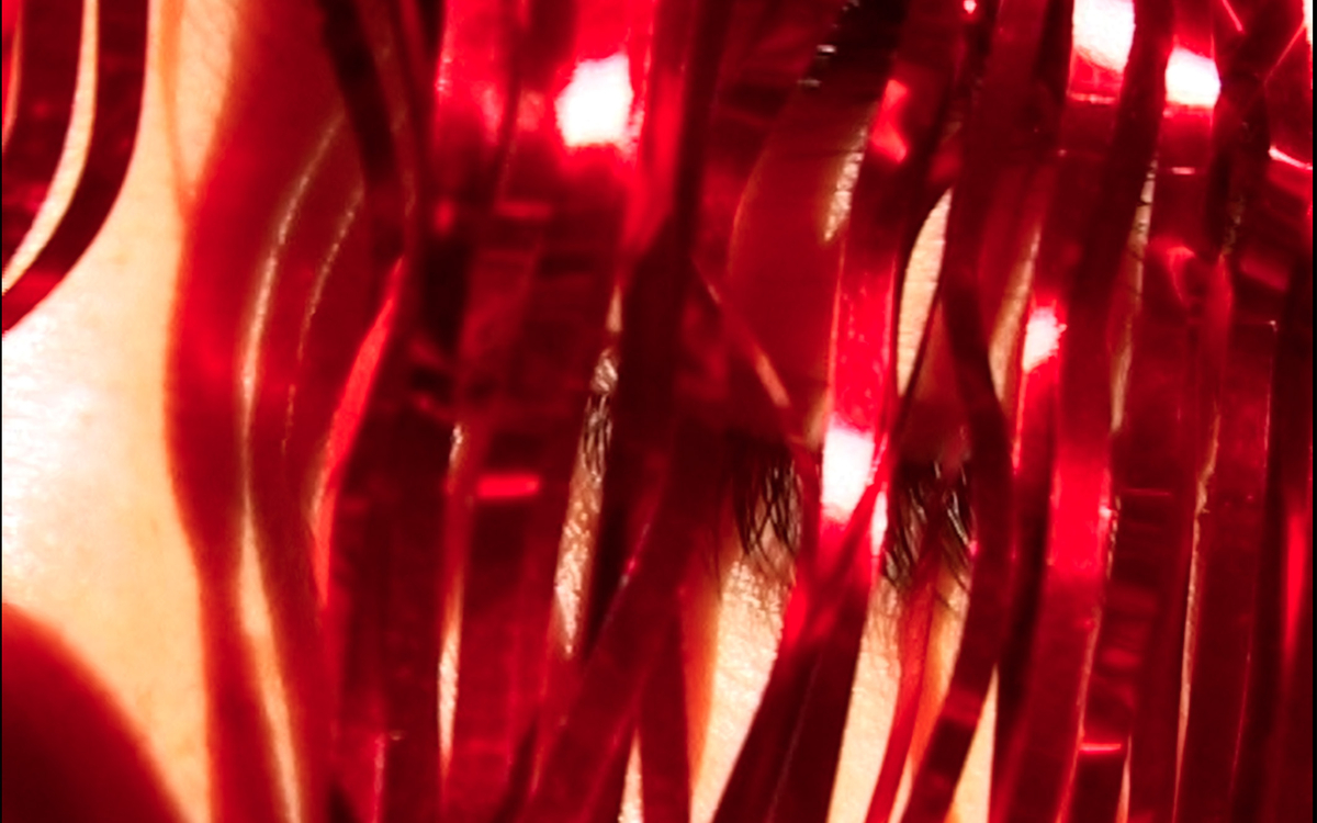 Un oeil se cache derrière des franges de rideaux rouge