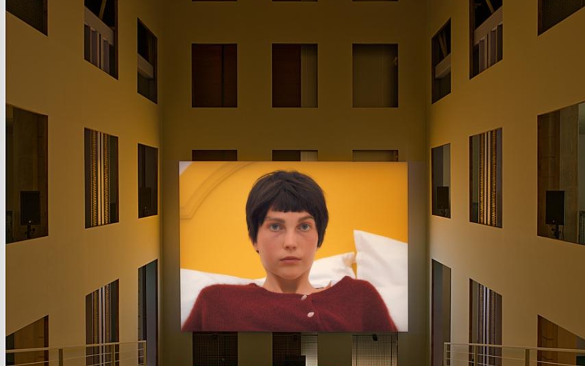 Vue de l'exposition 'Prom' de Diego Marcon à Lafayette Anticipations représentant un écran de cinéma avec une femme brune au milieu de fenêtres d'immeubles
