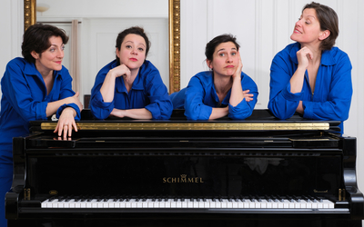 quatre femme en bleu de travail autour d'un piano