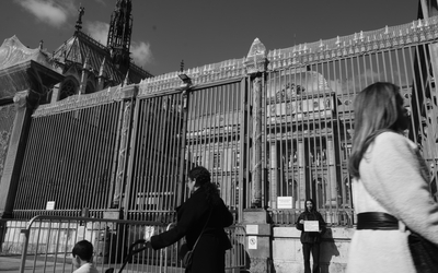 Photo en noir et blanc. Des passantes apparaîssent au premier plan. A l'arrière plan, une femme tient une pancarte où sont écrit les mots prononcés par le juge après une plainte pour viol. 