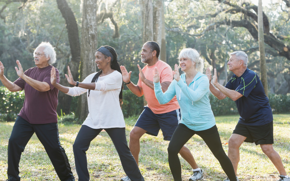 Groupe de participants pratiquant le Taichi en extérieur, réalisant des mouvements lents et synchronisés dans un parc