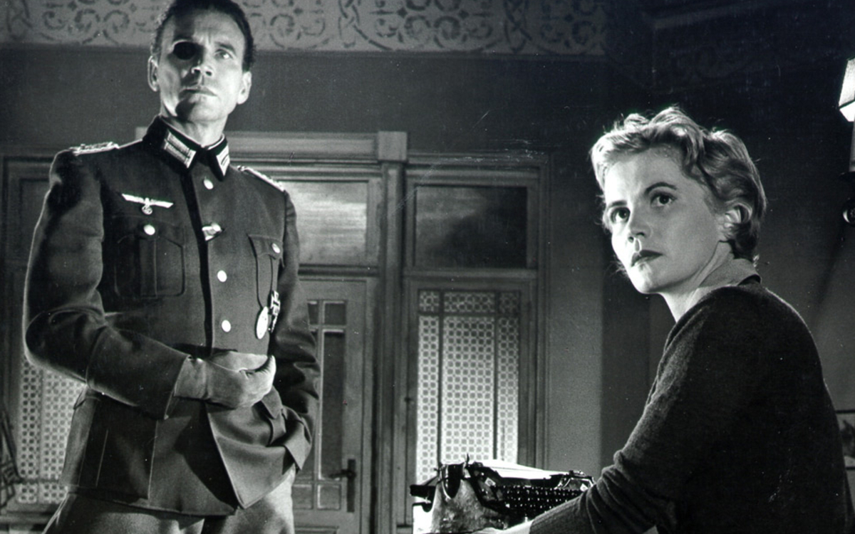 Un homme en uniforme de la Wehrmacht et une femme blonde regardent au loin, l'air un peu maussade, nous laissant nous demander ce qu'ils regardent.