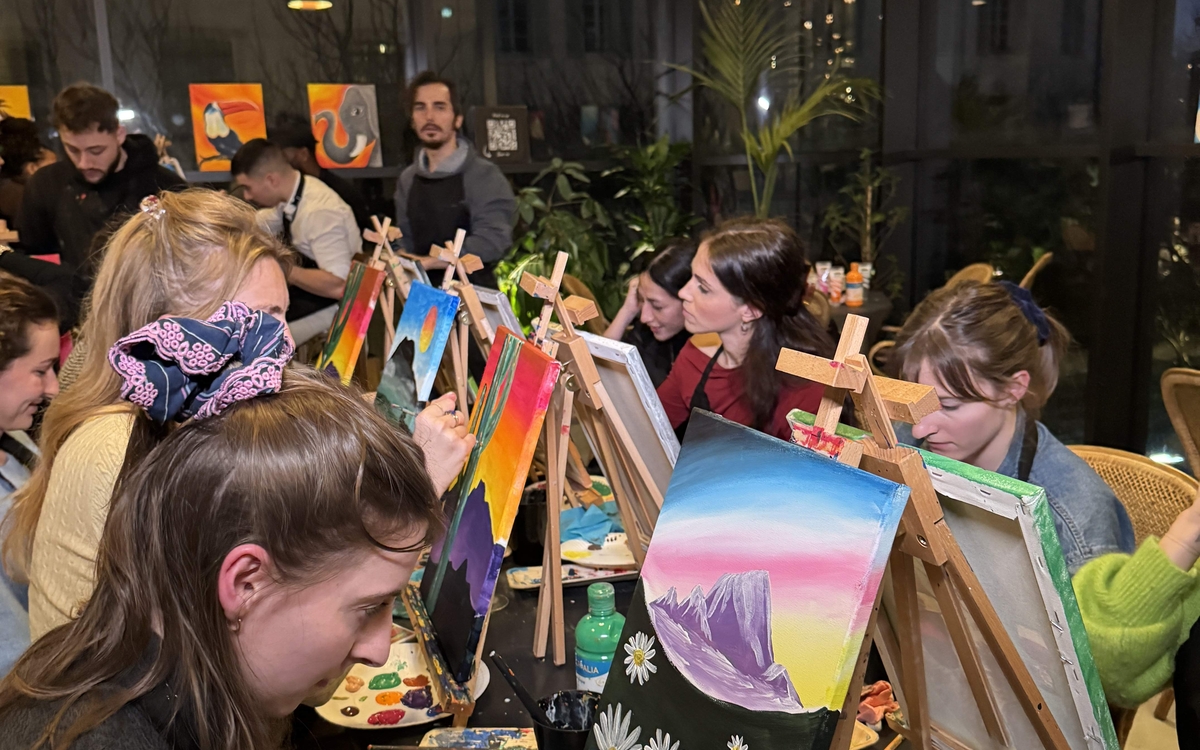 Personnes participant à un atelier de peinture à Paris, guidées par un artiste dans une ambiance conviviale et créative.